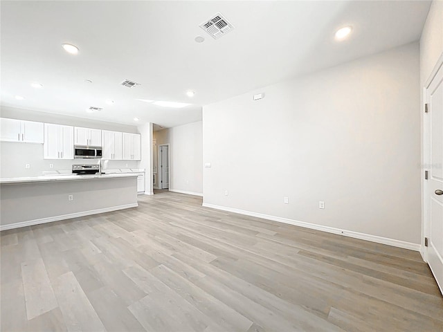 unfurnished living room featuring recessed lighting, visible vents, light wood-style flooring, and baseboards