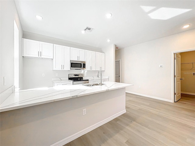 kitchen featuring visible vents, a sink, light stone counters, white cabinetry, and stainless steel appliances