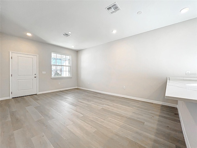 empty room with visible vents, baseboards, and light wood finished floors