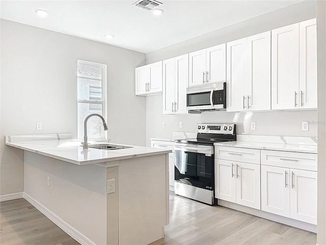 kitchen featuring visible vents, light wood-style flooring, appliances with stainless steel finishes, white cabinetry, and a sink