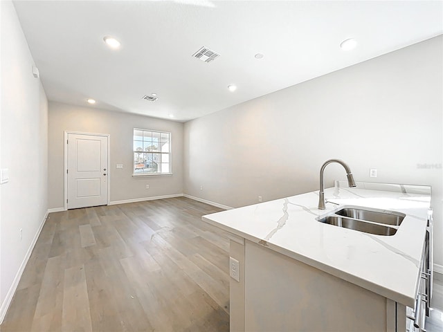 kitchen with light stone counters, visible vents, light wood-style flooring, recessed lighting, and a sink