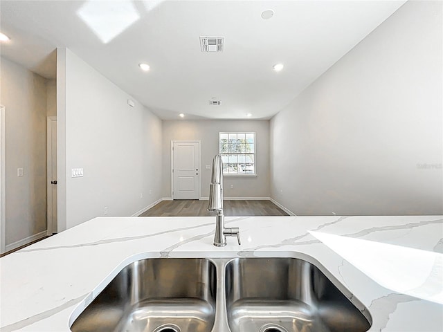 kitchen featuring light stone counters, wood finished floors, visible vents, recessed lighting, and a sink