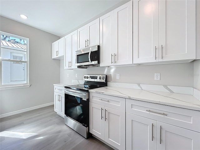 kitchen with baseboards, light stone countertops, light wood-style flooring, appliances with stainless steel finishes, and white cabinets