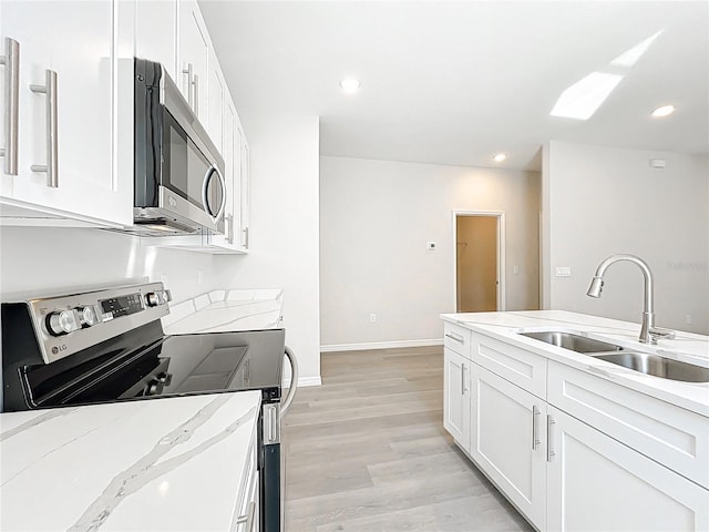 kitchen featuring a sink, light wood-style flooring, white cabinetry, and stainless steel appliances