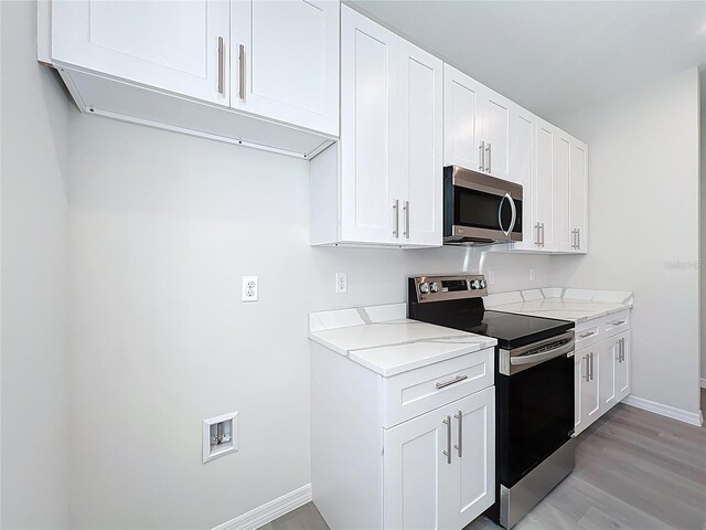 kitchen with white cabinets, light wood-style flooring, baseboards, and stainless steel appliances