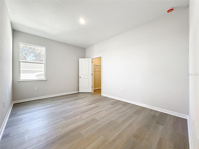 empty room with wood finished floors, baseboards, and a textured ceiling