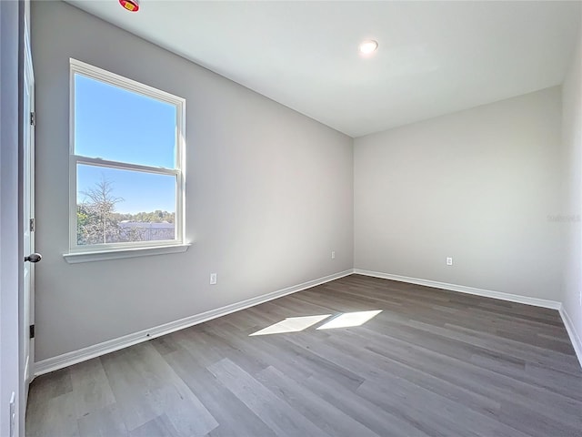 spare room with baseboards and wood finished floors