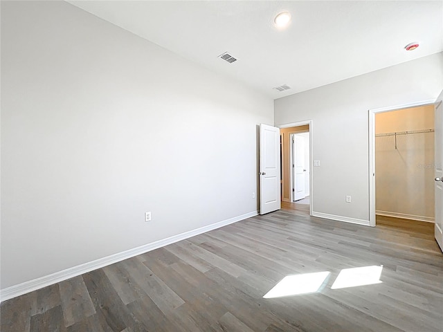 unfurnished bedroom with visible vents, baseboards, wood finished floors, and a spacious closet