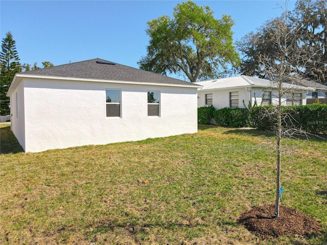 back of property featuring stucco siding and a lawn