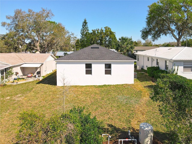 exterior space featuring stucco siding, a lawn, and roof with shingles