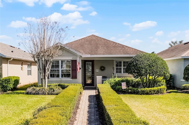 view of front of property featuring stucco siding, a front lawn, and a shingled roof