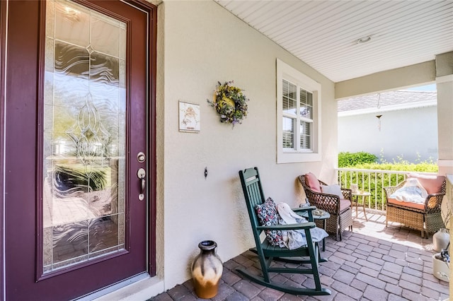 view of exterior entry with a porch and stucco siding