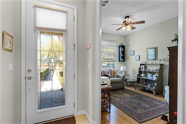 entrance foyer with visible vents, baseboards, wood finished floors, a textured ceiling, and a ceiling fan