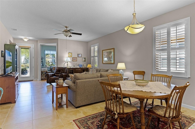 dining area featuring a ceiling fan, a healthy amount of sunlight, visible vents, and a textured ceiling