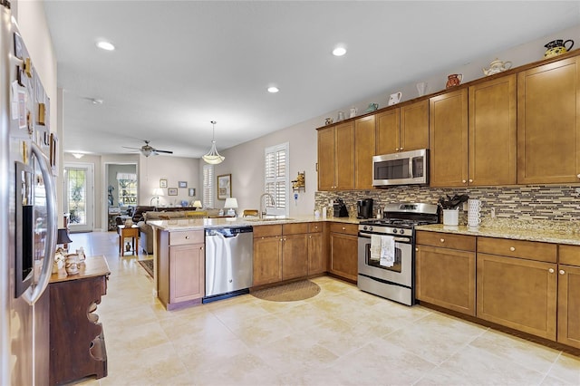 kitchen featuring brown cabinetry, appliances with stainless steel finishes, a peninsula, and a sink