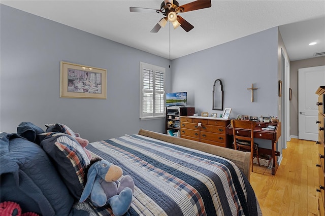 bedroom with light wood finished floors, visible vents, and a ceiling fan