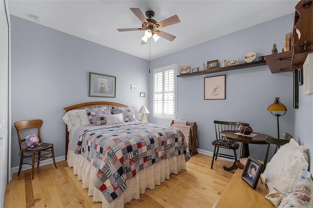 bedroom with light wood-style flooring, a ceiling fan, and baseboards