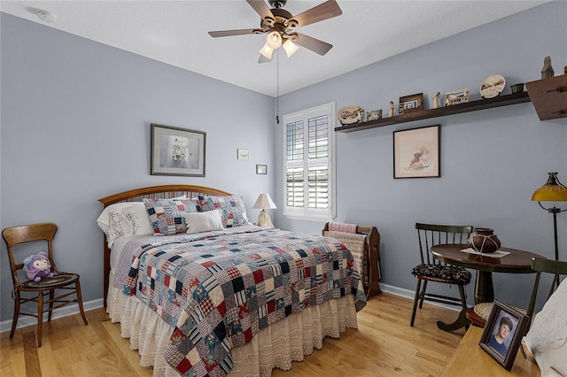 bedroom with a ceiling fan, baseboards, and wood finished floors