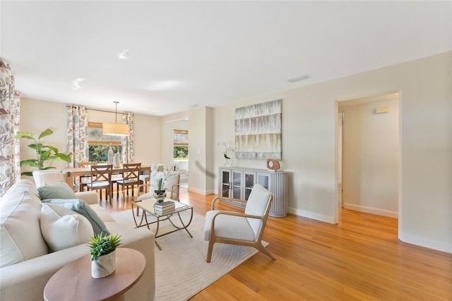 living area with visible vents, baseboards, and light wood finished floors