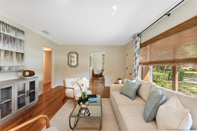 living area with wood finished floors, visible vents, and baseboards