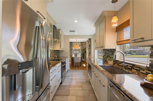 kitchen with a sink, decorative light fixtures, tasteful backsplash, dark stone counters, and appliances with stainless steel finishes