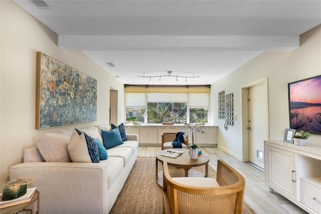 living area featuring light wood-type flooring, visible vents, baseboards, and rail lighting