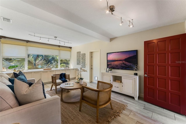 living room with baseboards, visible vents, wood tiled floor, track lighting, and beamed ceiling