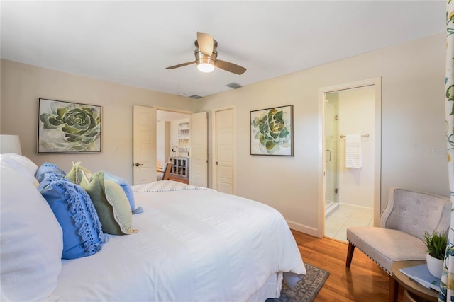 bedroom with baseboards, visible vents, ensuite bath, light wood-style flooring, and ceiling fan