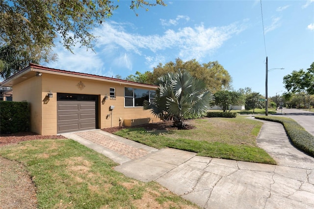 view of front facade featuring decorative driveway, a garage, concrete block siding, and a front lawn