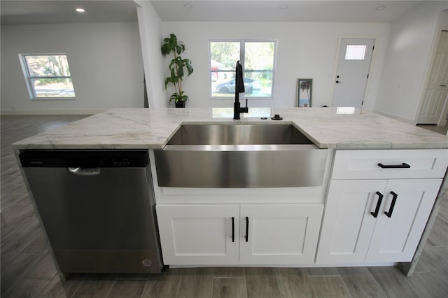 kitchen with a sink, white cabinets, light stone countertops, and stainless steel dishwasher