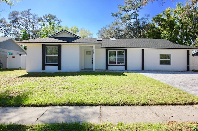 single story home featuring stucco siding, a front lawn, and fence