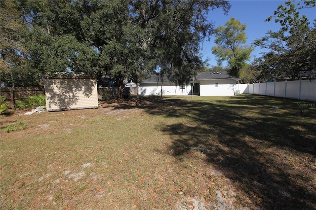 view of yard with an outdoor structure, a storage shed, and a fenced backyard