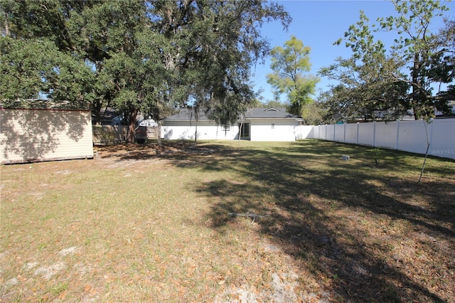 view of yard with a storage shed, an outbuilding, and a fenced backyard