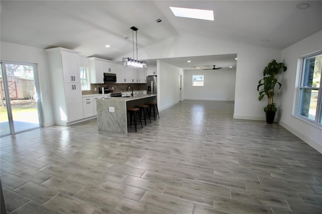 kitchen featuring a ceiling fan, a breakfast bar, plenty of natural light, appliances with stainless steel finishes, and open floor plan