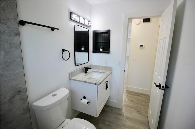 bathroom featuring vanity, toilet, baseboards, and wood finish floors