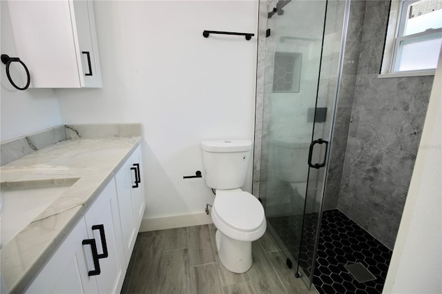 bathroom with wood finish floors, baseboards, toilet, a stall shower, and vanity