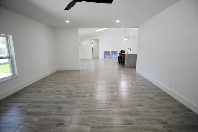 unfurnished living room featuring wood finish floors, recessed lighting, baseboards, ceiling fan, and vaulted ceiling