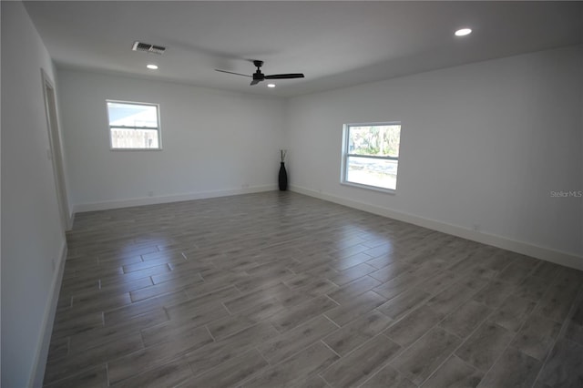 unfurnished room featuring a wealth of natural light, visible vents, recessed lighting, and wood finished floors