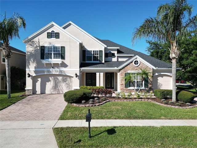 traditional home with stone siding, stucco siding, decorative driveway, and a front yard