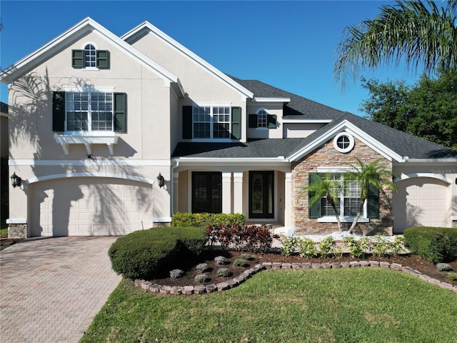 traditional home with a shingled roof, stucco siding, a garage, stone siding, and driveway