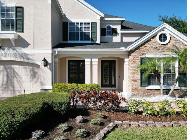 view of exterior entry with stone siding, stucco siding, and a garage