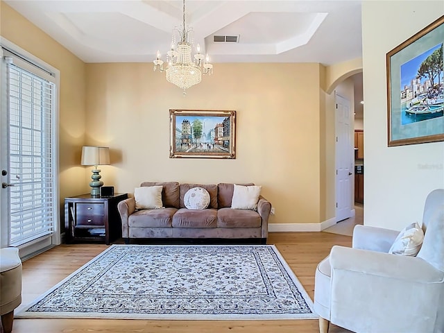 living area with visible vents, baseboards, light wood-type flooring, arched walkways, and a notable chandelier