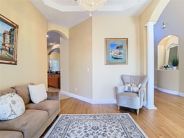 living room featuring baseboards, arched walkways, and light wood-style flooring