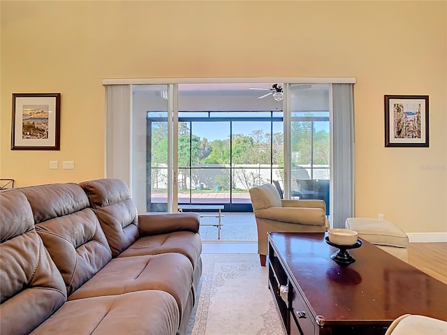 living area featuring baseboards, ceiling fan, and wood finished floors