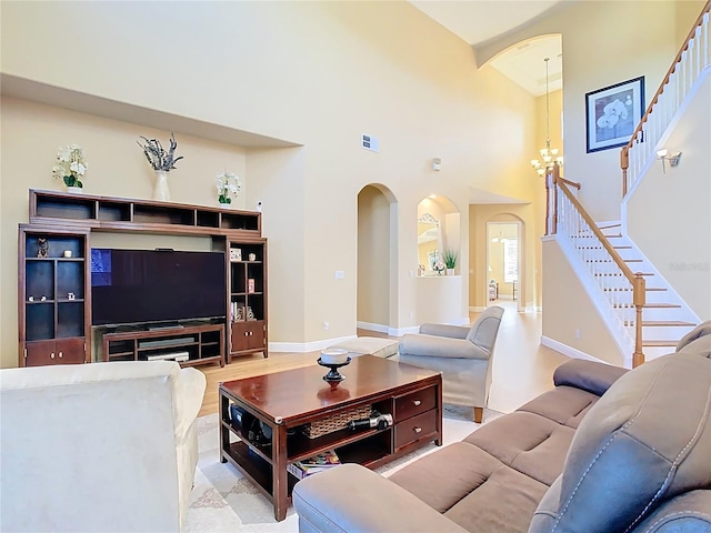 living area with arched walkways, stairway, and a towering ceiling