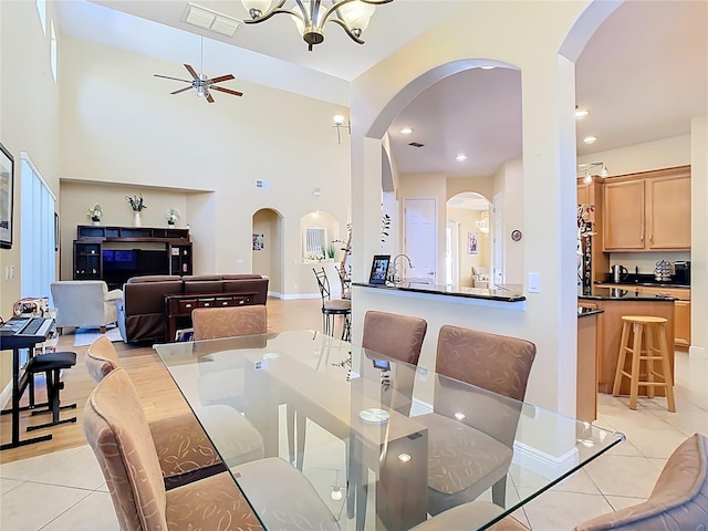 dining room featuring light tile patterned flooring, visible vents, ceiling fan with notable chandelier, and arched walkways