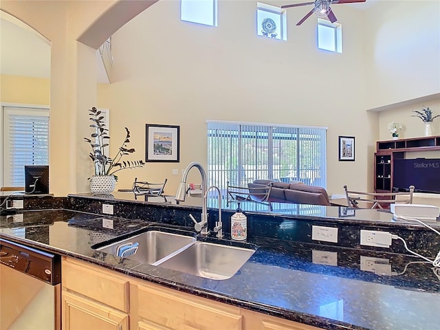 kitchen featuring arched walkways, ceiling fan, light brown cabinetry, a sink, and dishwasher