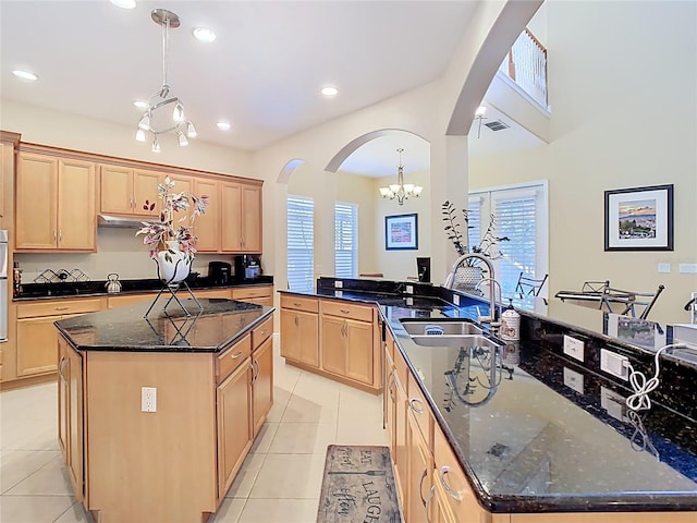 kitchen with light tile patterned floors, light brown cabinets, arched walkways, and a center island