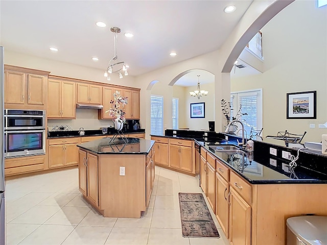 kitchen featuring a sink, arched walkways, a chandelier, and light brown cabinetry