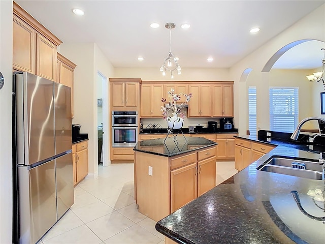 kitchen featuring light brown cabinetry, a kitchen island, appliances with stainless steel finishes, and a sink